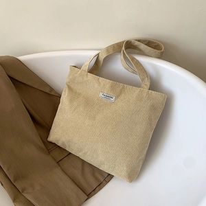 Detail of light khaki corduroy tote bag featuring a Fashion label in a stylish setting