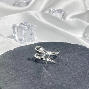 Detailed close-up of a silver snake-shaped ring on black stone with white silk background
