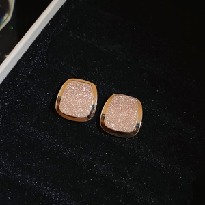 Close-up of square 18k rose gold earrings with shimmering glitter in black jewelry box