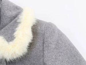 Close-up of gray woolen coat featuring a fluffy white faux fur collar and soft texture