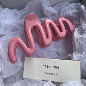 Pink wave-shaped jelly hair claw clip for women shown in a gift box with aesthetic setup