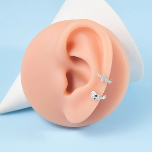 Detailed view of silver skull and cross earrings with micro-set zircons on ear model