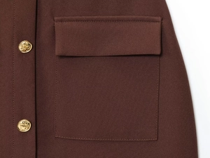 Close-up of brown textured midi dress featuring side flap pocket and gold embossed buttons