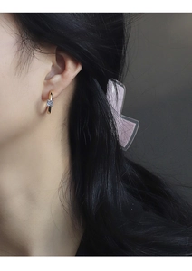 Close-up of gold C-shaped hoop earring with a square zircon on woman's ear