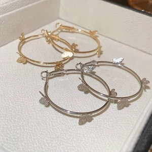 Detail of gold and silver butterfly hoop earrings on a white leather jewelry box