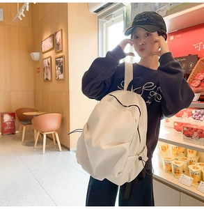 Detail view of cream oversized nylon backpack with side drawstring in a retail setting