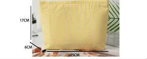 Detail view of seersucker makeup bag showing 25x17x6cm dimensions and yellow striped texture