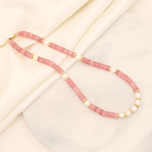 Detail of pink stone and white pearl necklace with gold clasp on marble tray