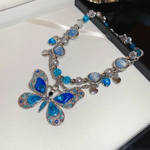 Détail du collier papillon en strass bleus avec perles et design en métal argenté