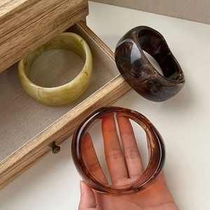 Macro detail of amber and marble resin bangles showcasing smooth glossy textures and swirls