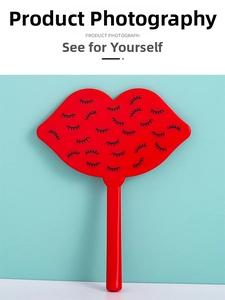 Macro detail of red lip-shaped hand mirror featuring a sleek black eyelash pattern design