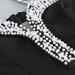 Detail of elegant black evening dress with white faux pearls and sparkling rhinestones
