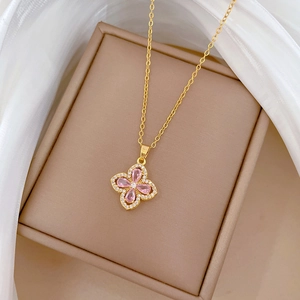 Macro shot of pink zircon clover pendant necklace in gold setting on silk background