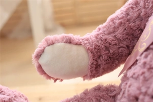 Close-up of pink teddy bear plush paws and soft silk lavender bow detail