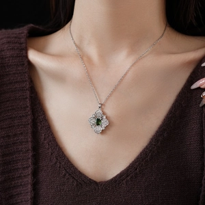 Close-up of elegant silver necklace with emerald green rectangular gemstone and zircon detail