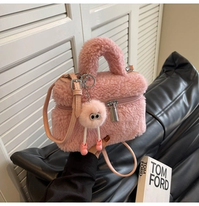 Detailed view of pink teddy plush bucket bag with cute monster charm and leather strap