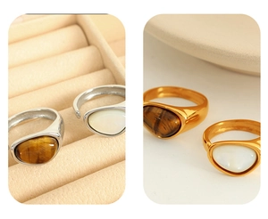 Detail view of gold and silver tiger eye rings on a soft beige jewelry background