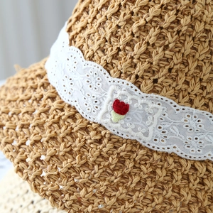 Macro detail of natural straw woven texture with white lace ribbon and small floral patch