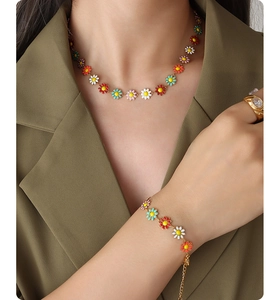 Detail of colorful daisy necklace and bracelet set on model with olive green blazer