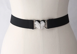 Détail d'une ceinture élastique noire avec boucle en forme de cœur argenté sur mannequin