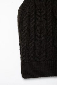 Close-up of black cable knit texture and ribbed hem on a cozy turtleneck sweater vest