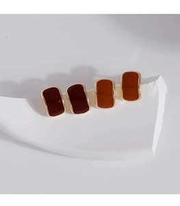 Macro view of rectangular amber enamel earrings with gold trim on white background