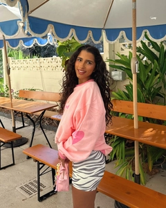 Pink crewneck sweatshirt with stylish zebra print skirt shown in a cafe setting