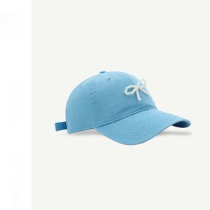 Close-up of light blue cotton baseball cap with delicate pearl bow detail and side buckle