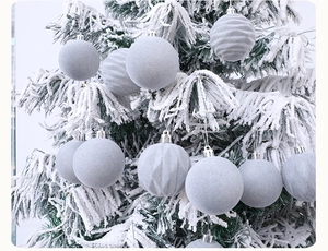 Detail of grey Christmas ornaments with matte, ribbed, and diamond textures on snowy tree