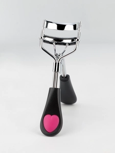 Detail of stainless steel eyelash curler with built-in comb and pink heart handle grip