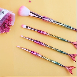 Detailed view of four mermaid-shaped makeup brushes with gradient electroplated handles