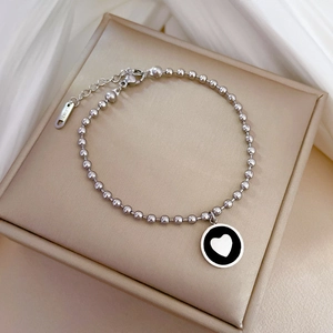 Gros plan détaillé du bracelet à billes en acier titane avec pendentif cœur sur soie