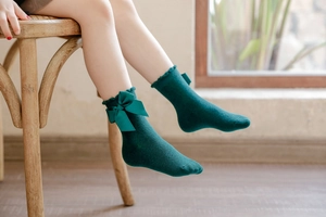 Detailed view of dark green kids cotton socks with large bow and ruffled lace cuff