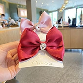 Close-up of satin bow hair clips with a large heart-shaped rhinestone center in pink and red