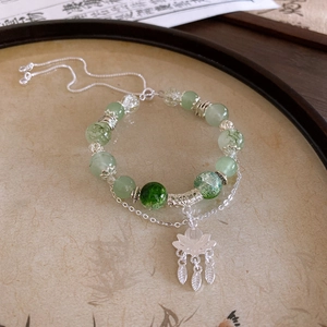 Zen-style bracelet featuring green lotus flower tassel and silver metal accents