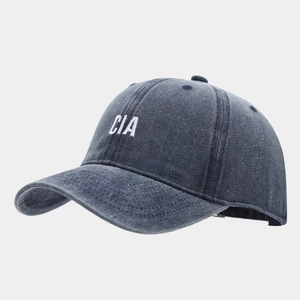 Close-up of white CIA embroidery on dark grey washed denim baseball cap with vintage texture