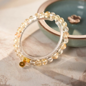 Detailed view of yellow citrine beaded bracelet with golden coin pendant on marble