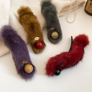 Detail view of plush faux fur hair clips in purple and brown with golden Lucky charms