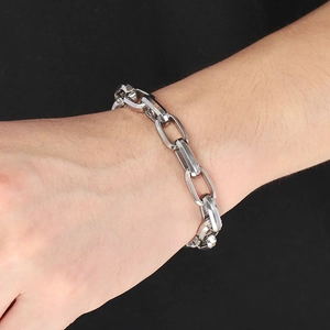 Close-up of a silver rectangular link chain bracelet worn on a wrist against black background