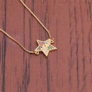 Macro detail of gold star pendant necklace with colorful zircon spelling MOM on wood
