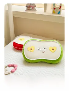 Detail von süßen Plüschkissen in Fruchtform mit Herzbestickung auf weichem Bett