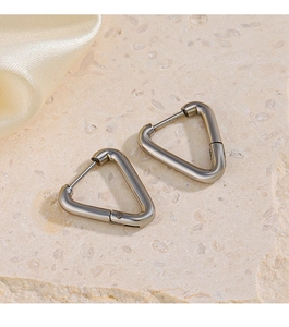 Macro detail of silver triangle hoop earrings in stainless steel on stone and silk background