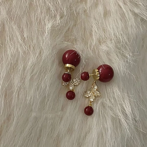 Detailed close-up of butterfly earrings with red pearls and gold metal on fur