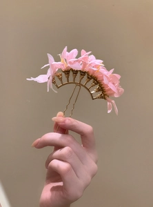 A detailed macro view of an elegant handmade pink fabric flower hairpin for hair updos