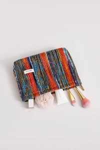 Detail of colorful woven bohemian cosmetic bag showing zipper closure and storage capacity