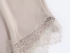 Dettaglio ravvicinato del tessuto satinato color champagne con pizzo delicato