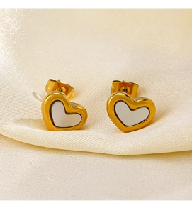 Macro shot of gold heart studs with white pearlescent inlay on beige silk fabric