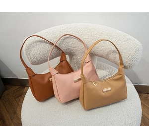 Detailed shot of three textured leather shoulder bags with gold accents and leaf pendants
