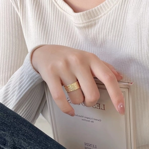 Close-up of a wide textured gold 925 silver ring worn by a model holding a book