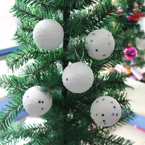 Close-up of five white flocked Christmas ornaments with colorful star sequins on green tree